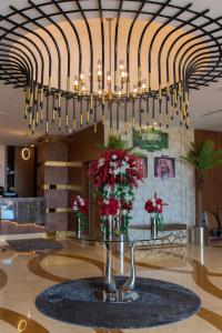 een grote kroonluchter in een lobby met rode bloemen bij Emerald Hotel in Jeddah