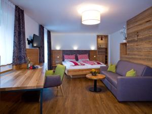 ein Wohnzimmer mit einem Bett und einem Sofa in der Unterkunft Landgasthof Lusenblick in Grafenau