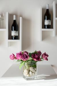 a vase with roses and two bottles of wine at Appartamento Al Forte in Nago-Torbole +35 photos