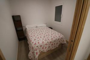 a small bedroom with a bed with a flowered blanket at Buen Camino Melide in Melide