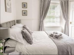 a bedroom with a bed with white sheets and a window at Tavistock Town House in Tavistock