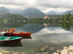 two boats are docked on a lake with mountains at No.1 Apartment House Oliver in Štrbské Pleso