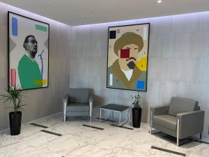 a waiting room with two chairs and portraits on the wall at Апартаменты в ЖК LEGENDA, Алматы (Apartment in LEGENDA Residence) in Almaty