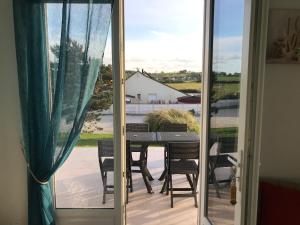 a glass door leading to a patio with a table and chairs at La Villa Port Winston - Face Mer B&B in Saint-Côme-de-Fresné