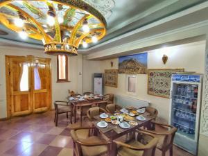 a dining room with tables and chairs and a chandelier at KALA Khiva in Khiva