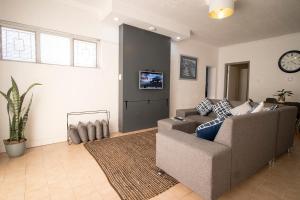 sala de estar con sofá y reloj en la pared en 16 st Johns - Apartment, en Port Shepstone