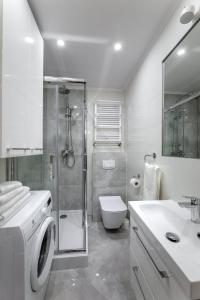 uma casa de banho branca com um chuveiro e uma máquina de lavar roupa em Apartament Łąkowa 2 em Kudowa-Zdrój