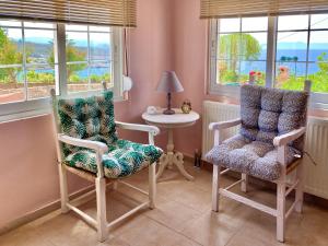 Zimmer mit 2 Stühlen, einem Tisch und Fenstern in der Unterkunft Seashore Apartments in Chorafakia