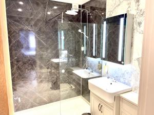 a bathroom with a shower and two sinks and a mirror at Gwesty Gadlys Hotel in Cemaes Bay