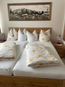 2 camas con almohadas blancas y un cuadro en la pared en Gästehaus-Pension Bendler, en Kirchdorf in Tirol