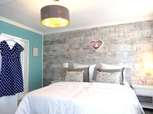 ein Schlafzimmer mit einem Bett und einem an der Wand hängenden Kleid in der Unterkunft Strandhotel Villa Louisa & Appartementhäuser Villa Josephine und Villa Christine in Juliusruh