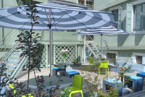 een patio met twee blauwe parasols en stoelen en tafels bij Campanile Annecy Centre - Gare in Annecy