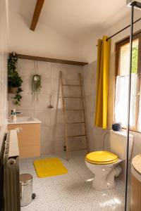 uma casa de banho com um WC amarelo e um lavatório. em Gites de la Lurette - T3 lumineux et spacieux dans cadre calme et verdoyant em Cazilhac