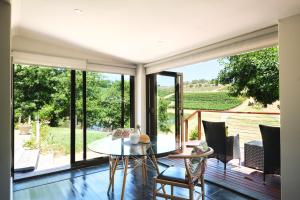 Habitación con una mesa de cristal y sillas en una terraza. en Alluvia Boutique Winery & Luxury Accommodation, en Stellenbosch