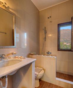 ein Badezimmer mit Waschbecken, Toilette und Spiegel in der Unterkunft Achelatis Traditional Guest Houses in Areopoli + 57 Fotos