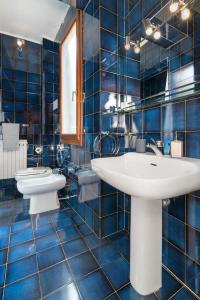 a blue tiled bathroom with a sink and a toilet at Ca’ Pesaro rooftop terrace apartment. in Venice +34 photos