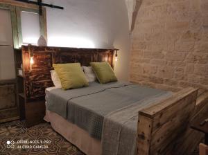 sypialnia z drewnianym łóżkiem i 2 zielonymi poduszkami w obiekcie Dimora 'a Petr - Suite 'a Petr w mieście Ceglie Messapica
