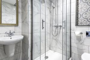 a white bathroom with a shower and a sink at The George Hotel in Colchester