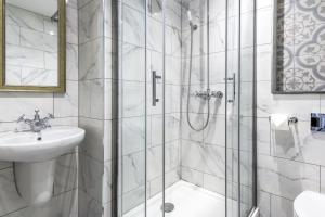 baño blanco con ducha y lavamanos en The George Hotel, en Colchester
