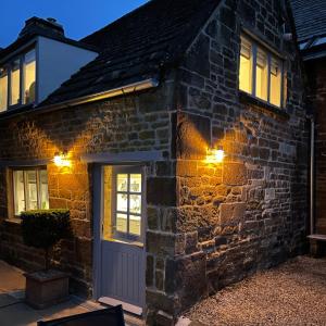a stone house with a blue door and lights at Box Barn - Stylish Accommodation in Rutland in Uppingham