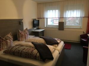 a hotel room with a bed and a television at Café Feldmann & Pension in Bad Sooden-Allendorf
