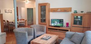 ein Wohnzimmer mit Stühlen, einem TV und einem Tisch in der Unterkunft Ferienwohnung 4 im Haus am See mit Wintergarten und Terrasse in Seedorf