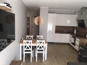 a kitchen with a table and stools in a room at Apartament Silence Baltic Skandynawski in Pobierowo