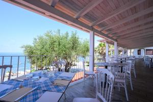 un patio con mesas y sillas y el océano en Villaggio Stella del Sud & Resort en Pisciotta