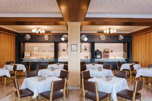 una sala da pranzo con tavoli e sedie bianchi di Seegasthof Hois'n Wirt - Hotel mit Wellnessbereich a Gmunden