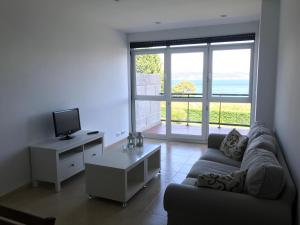 フィニステレにあるApartamento con terraza primera linea de playaのソファとテーブルとテレビのあるリビングルーム