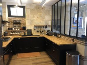 a kitchen with black cabinets and a stone wall at le repère du marché in Bergerac