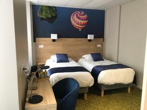 une chambre d'hôtel avec 2 lits et un ballon sur le mur dans l'établissement Logis Hôtel de Paris, à Murol