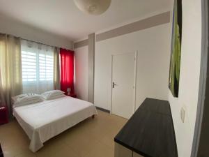 a bedroom with a white bed and a red window at Villa Créole Domaine privé de l'Anse des Rochers in Saint-François +34 photos