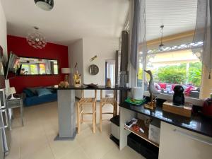 a kitchen and living room with red walls and a counter at Villa Créole Domaine privé de l'Anse des Rochers in Saint-François
