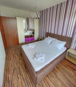 um quarto com uma cama com lençóis brancos e um espelho em Sunset Sea View Apartament em Mamaia