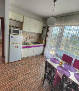 a kitchen with a table and a kitchen with purple chairs at Sunset Sea View Apartament in Mamaia