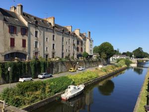 a boat in a river in front of buildings at La Promenade - Appartement de charme avec vue sur le canal et ses écluses - Centre historique in Redon