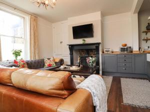a living room with a leather couch and a fireplace at No 19, Haworth in Keighley