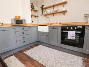 una cocina con armarios grises y horno negro en No 19, Haworth en Keighley