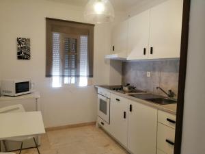 een keuken met witte kasten en een wastafel bij Room in Lovely cottage house Habitaciones en Chalet en Cadiz San Fernando in San Fernando