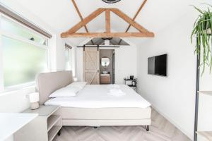 una camera bianca con letto e TV di Be So Suite a Zandvoort