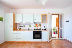 La cuisine est équipée de placards blancs et d'un four avec plaques de cuisson. dans l'établissement appartamento la veranda sul mare a Sampieri, à Sampieri