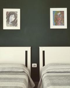 - une chambre avec 2 lits et 2 photos sur le mur dans l'établissement MEME'S HOUSE, à Locri