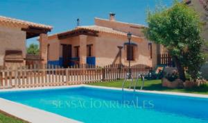 a villa with a pool in front of a house at Casas Rurales Lagunas de Ruidera - Piscina in Ossa de Montiel