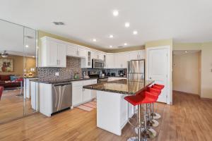 a kitchen with white cabinets and red stools at Ground floor beachfront beauty! Steps to the beach and pool in South Padre Island