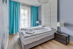 sypialnia z łóżkiem z niebieskimi zasłonami i oknem w obiekcie Grand Apartments - Szafuza Apartment Gdańsk Szafarnia w Gdańsku