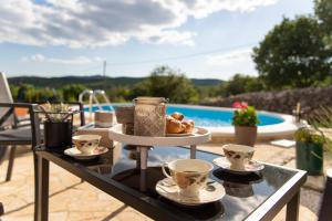 a tray of food and cups on a table next to a pool at Holiday Home Sego with Private Pool in Veliki Broćanac