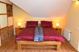 a large bed with red sheets in a room at Villam Apartment in Maribor