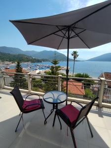 stół, 2 krzesła i parasol na balkonie w obiekcie Apartments Danilo w mieście Herceg Novi