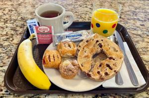 a tray of breakfast food with a banana and a cup of coffee at Oasis Guest House in Boston +8 photos
